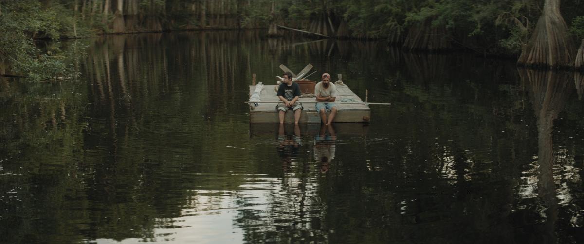 Film still: Tyler and Zak sit resting on a river float