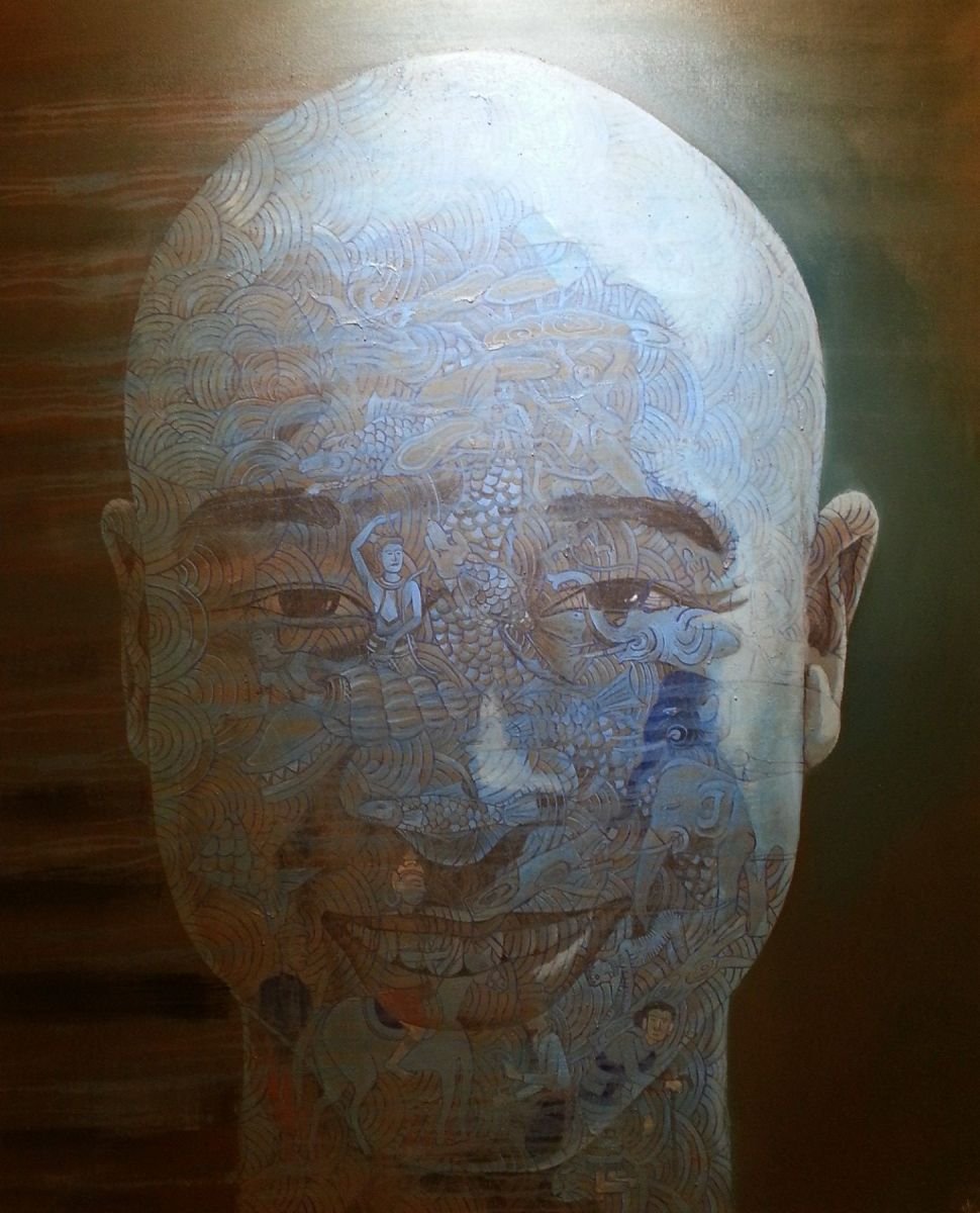 Painting: Cast in a blue hue is the portrait of a man, his skin filled with opaque iconography, nature, fan-motifs and a frail man etc.