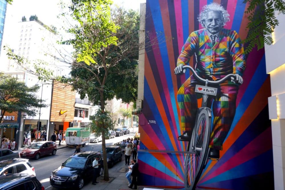 Bright colourful mural, featuring a smiling Albert Einstein riding a bike