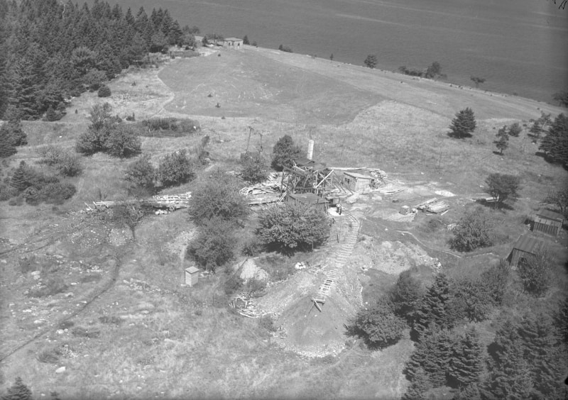 Black and white photograph showing a digs and a collapsed wooden structure on Oak Island