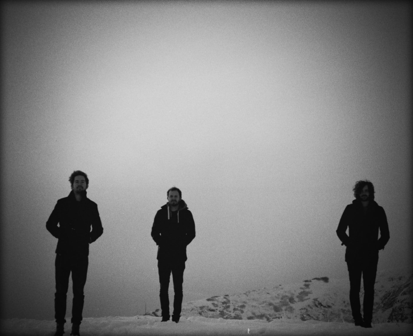 Black and white atmospheric photo of the band standing in snow.