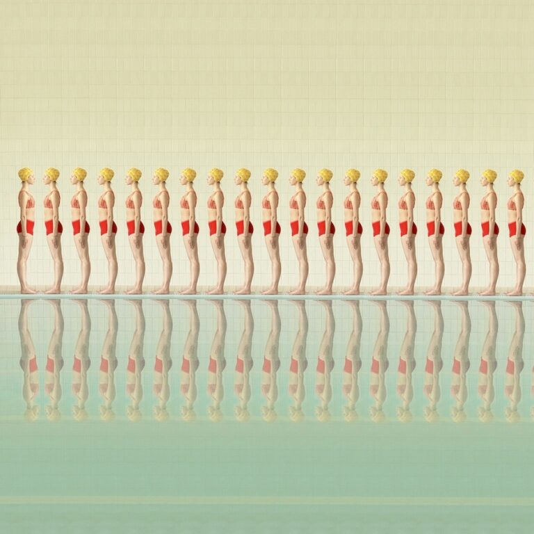 Photograph: At a swimming pool a row of women (same repeating woman) are wearing red swimsuits and yellow caps and face toward the left. At the end of this row one of the women is facing the opposite direction and is instead directly facing them.